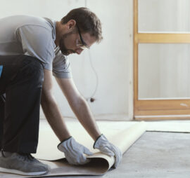Professional contractor removing an old linoleum flooring: home renovation concept